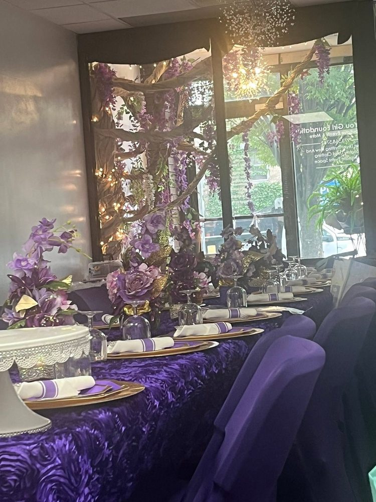 Long table set with gold chargers beneath a wisteria feature